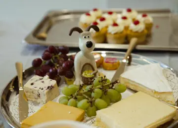 Gromit figurine in the centre of a cheese board. 