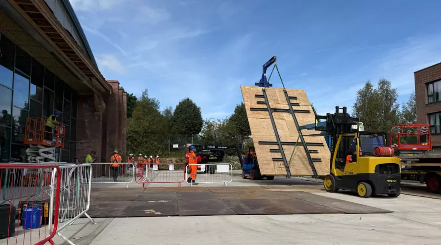 YTL Construction workers in safety gear operate machinery to carefully lift restored wooden doors  at The Hangar at Brabazon.