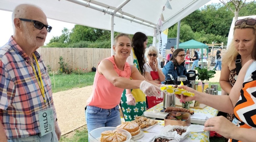 Residents at Brabazon gather under a gazebo on The Green at Brabazon, serving cakes to other residents at Brabfest.