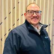 Man with short hair and glasses smiling at the camera