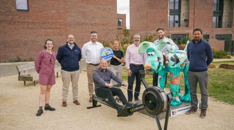 Eight YTL Group staff gather around a rowing maching situated next to 'The Birds' Gromit Sculpture at Brabazon.