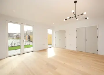 A bright living room with French doors and built-in storage cupboards.