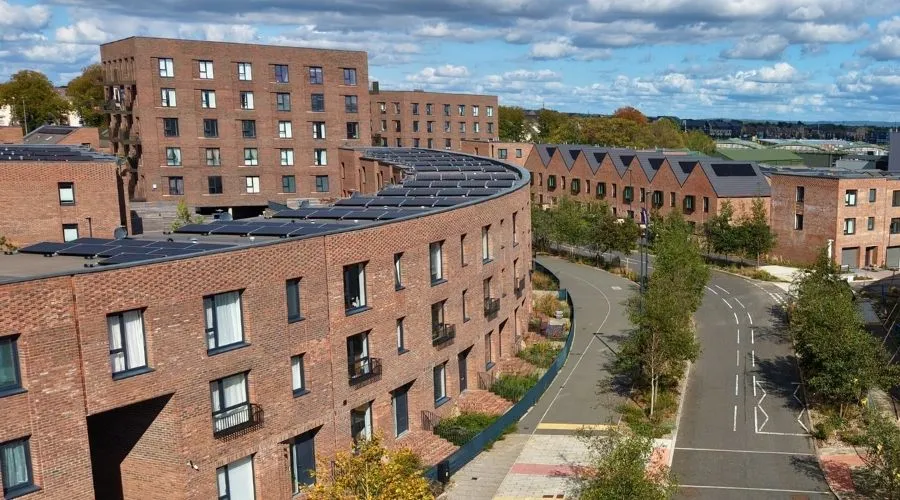 Tree-lined traffic-free pedestrian walking and cycle route passing in front of the red-brick houses and apartments at Brabazon in Bristol.