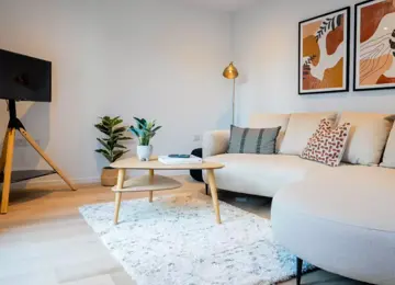 Modern living room, showcasing a cream sofa, white rug and wooden coffee table in The Burney view home at Brabazon, rbustol 