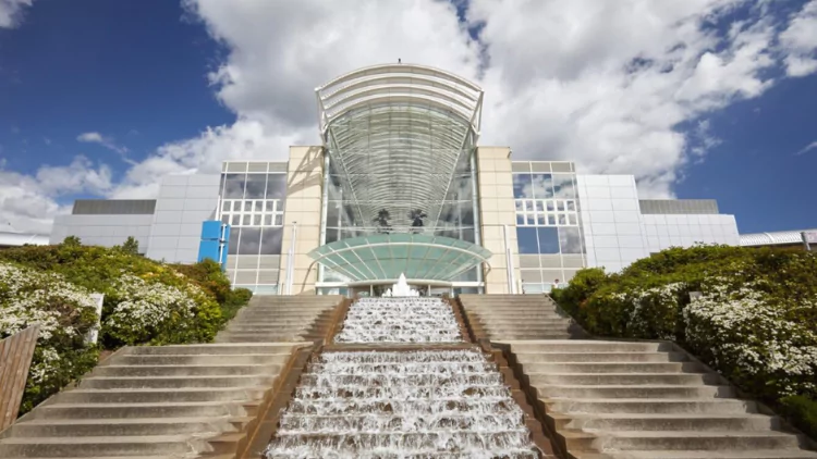 A large shopping mall with a glass entrance and a cascading outdoor man-made waterfall