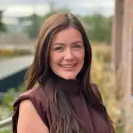 Caroline Bryant Close up photograph of a smiling young woman with long brunette hair.