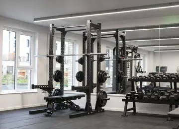 Clean and modern gym with squat rack and free weights area.