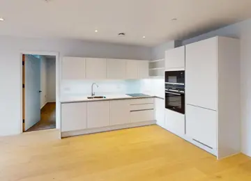 L-shaped fitted kitchen with integrated kitchen appliances and wood flooring.