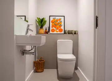 Modern downstairs W/C bathroom styled with orange and green accessories.